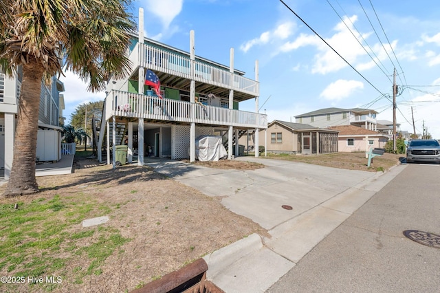 rear view of house with concrete driveway and stairs