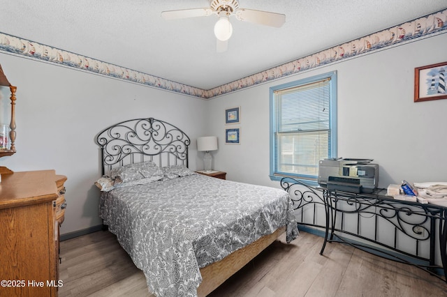 bedroom with ceiling fan, wood finished floors, baseboards, and a textured ceiling