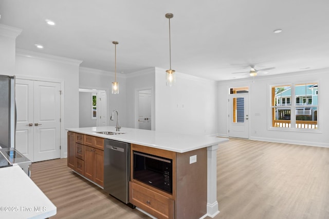 kitchen featuring black microwave, a sink, light wood finished floors, a healthy amount of sunlight, and stainless steel dishwasher