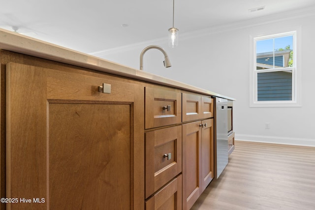 interior space featuring brown cabinetry, ornamental molding, baseboards, light wood-type flooring, and a sink