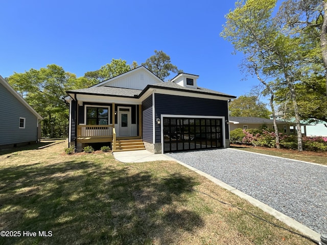 view of front of house featuring a front lawn, covered porch, gravel driveway, roof with shingles, and an attached garage