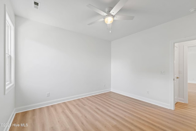 spare room with baseboards, a ceiling fan, light wood-style flooring, and a wealth of natural light
