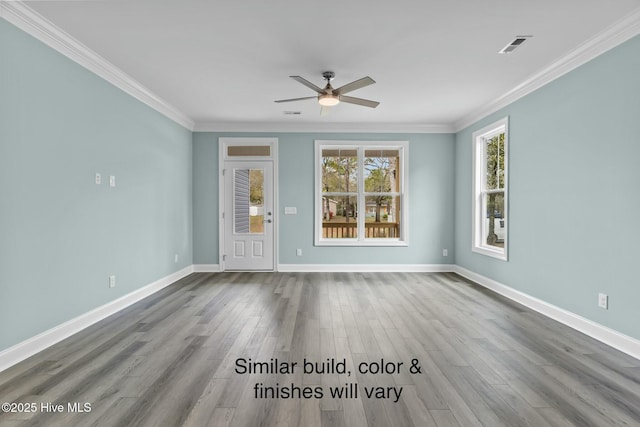 spare room featuring visible vents, wood finished floors, baseboards, and ornamental molding