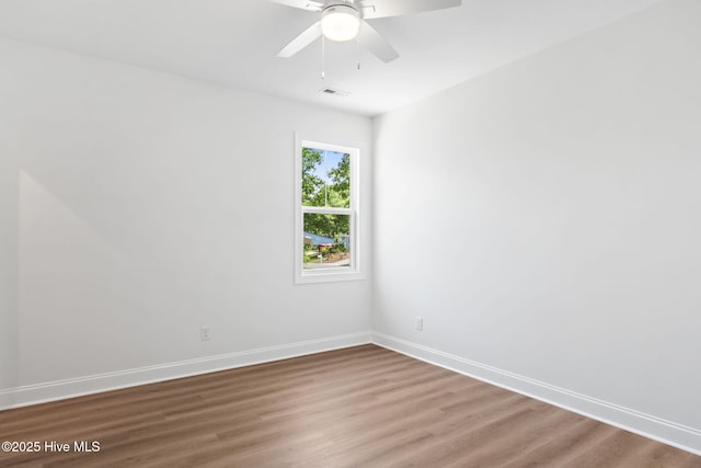 empty room with ceiling fan, baseboards, visible vents, and wood finished floors