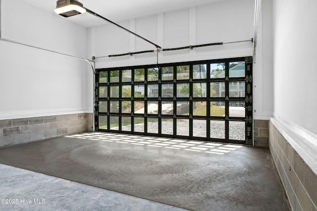 garage featuring concrete block wall and a garage door opener