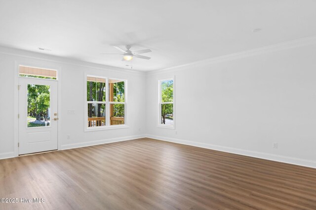 empty room featuring crown molding, ceiling fan, baseboards, and wood finished floors