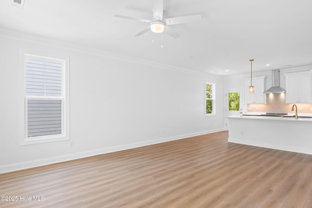 unfurnished living room with crown molding, a ceiling fan, recessed lighting, light wood-type flooring, and a sink