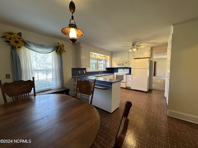 interior space with baseboards, a peninsula, white cabinets, white appliances, and a sink