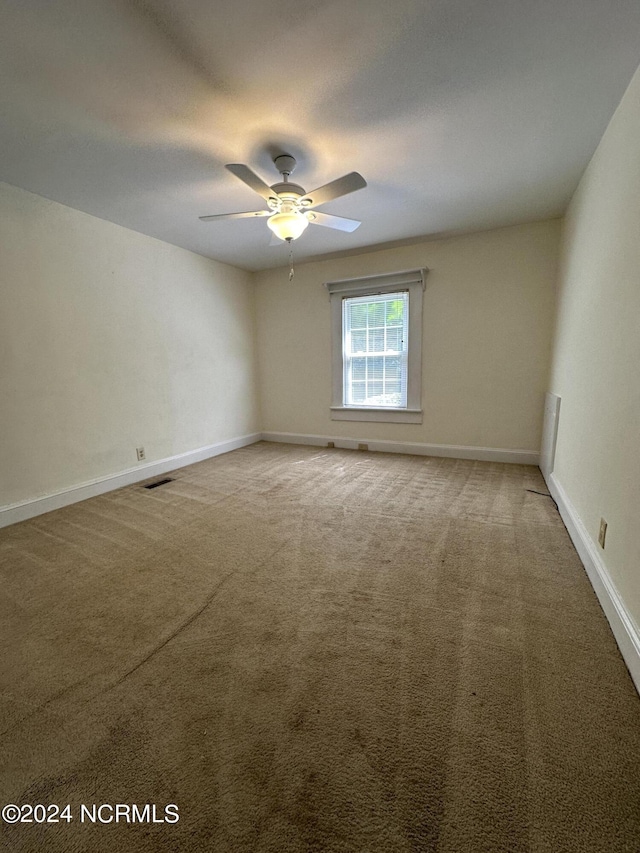 carpeted spare room featuring a ceiling fan, baseboards, and visible vents