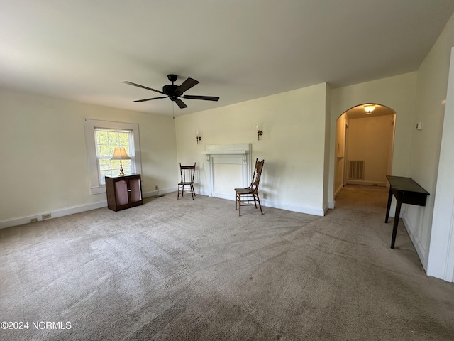 unfurnished living room featuring baseboards, visible vents, arched walkways, ceiling fan, and carpet flooring