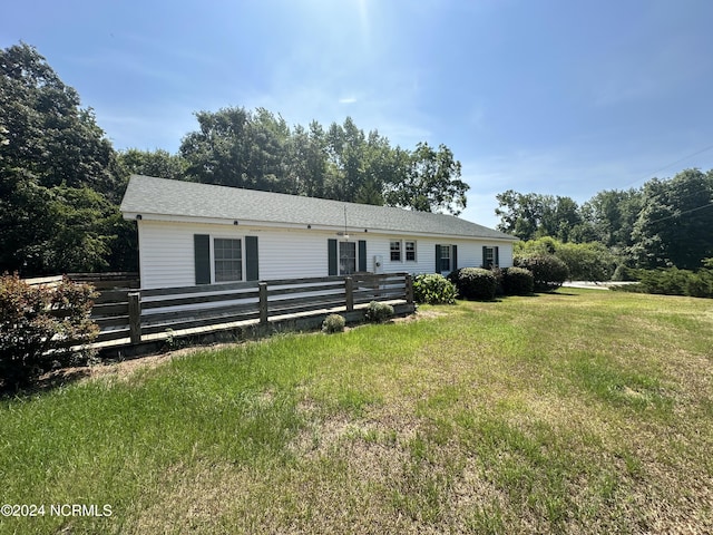 view of front of house with a front lawn, fence, and roof with shingles