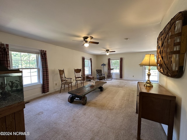 sitting room featuring a ceiling fan, light colored carpet, and baseboards