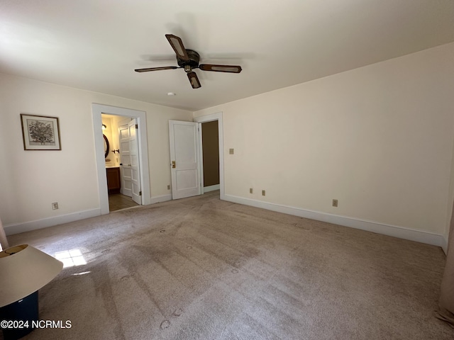 unfurnished bedroom featuring baseboards, light carpet, ceiling fan, and ensuite bathroom