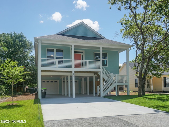 coastal inspired home with a front lawn, stairway, a porch, roof with shingles, and driveway