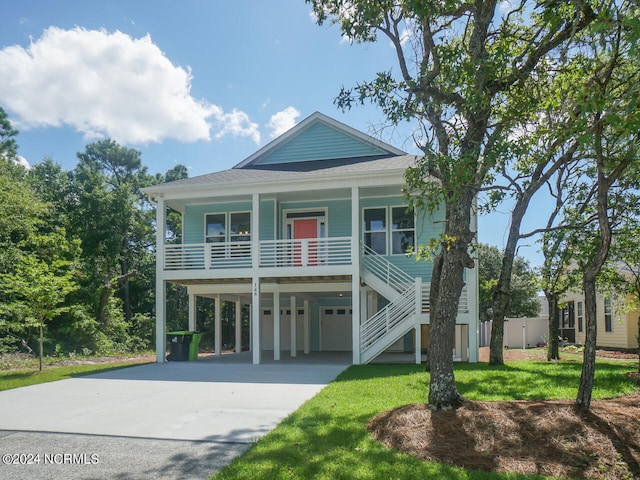 beach home featuring a front yard, stairway, driveway, a porch, and a carport