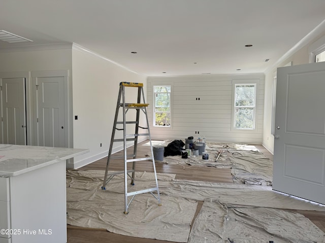 living room featuring a healthy amount of sunlight, wood finished floors, baseboards, and ornamental molding