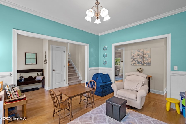 living area featuring an inviting chandelier, stairway, wood finished floors, and wainscoting