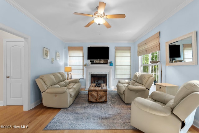 living room featuring ornamental molding, ceiling fan, baseboards, and wood finished floors