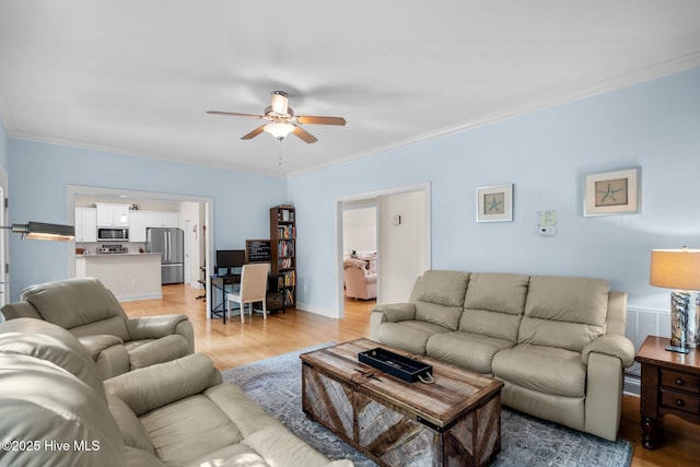 living area featuring light wood finished floors, a ceiling fan, and ornamental molding