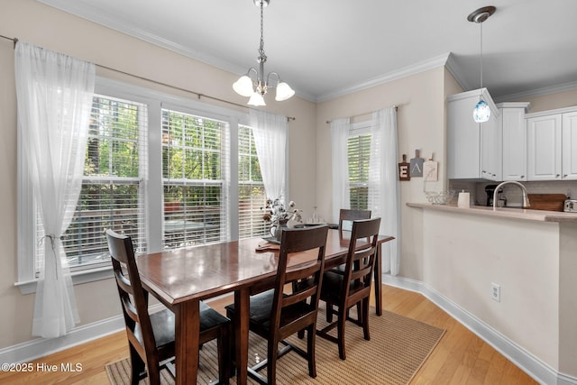 dining space with light wood-style flooring, baseboards, ornamental molding, and a chandelier