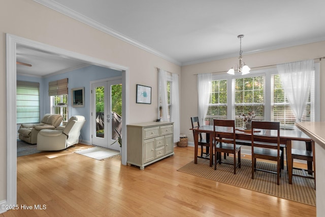 dining area featuring light wood-style flooring, a wealth of natural light, and ornamental molding