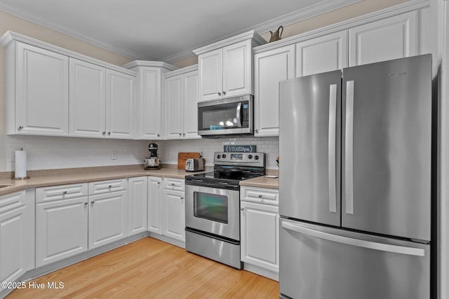 kitchen with white cabinetry, light countertops, ornamental molding, and stainless steel appliances