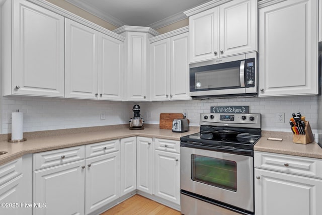 kitchen featuring stainless steel appliances, tasteful backsplash, ornamental molding, and white cabinetry