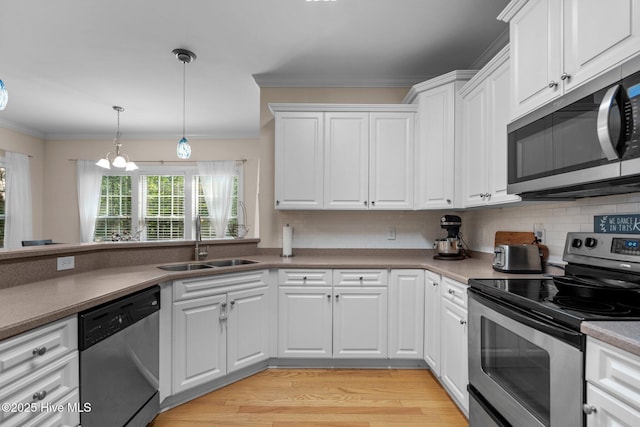 kitchen featuring ornamental molding, appliances with stainless steel finishes, white cabinetry, and a sink