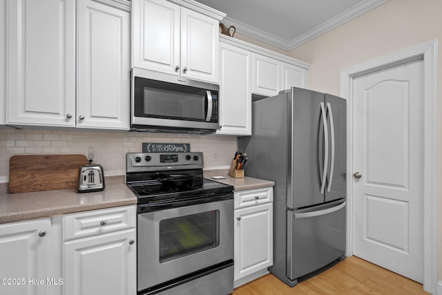 kitchen featuring backsplash, white cabinets, stainless steel appliances, and crown molding