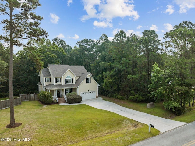 view of front of property featuring a front yard, fence, a forest view, an attached garage, and concrete driveway