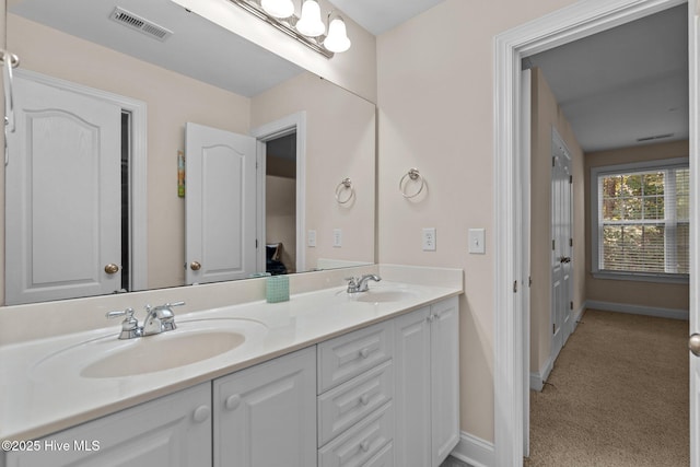 bathroom with double vanity, visible vents, baseboards, and a sink