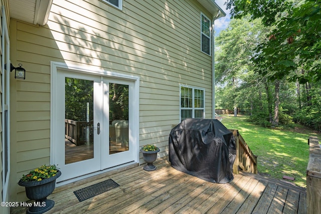 wooden deck featuring area for grilling, a yard, and french doors