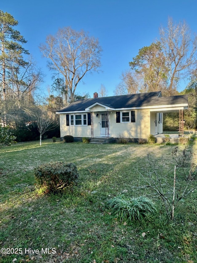 view of front of house with a carport, a front yard, and a chimney