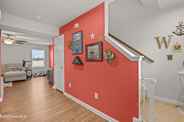 corridor featuring stairway, baseboards, and light wood-type flooring