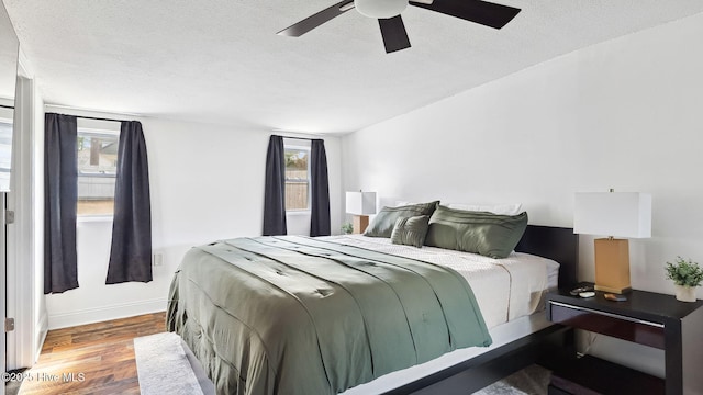 bedroom with a ceiling fan, multiple windows, wood finished floors, and a textured ceiling