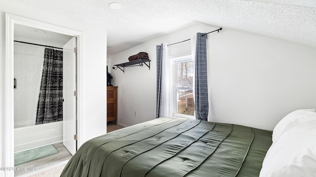 bedroom with lofted ceiling, wood finished floors, and a textured ceiling