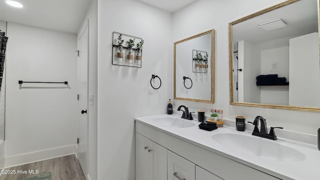 full bathroom featuring double vanity, wood finished floors, and a sink