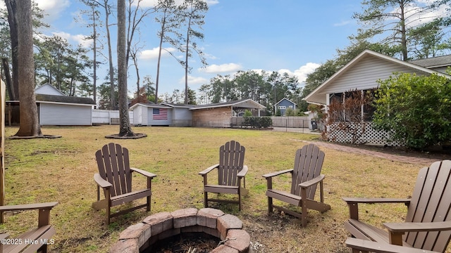 view of yard with a fire pit, a storage shed, an outdoor structure, and fence