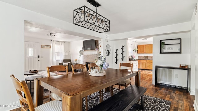 dining area with dark wood finished floors and a brick fireplace