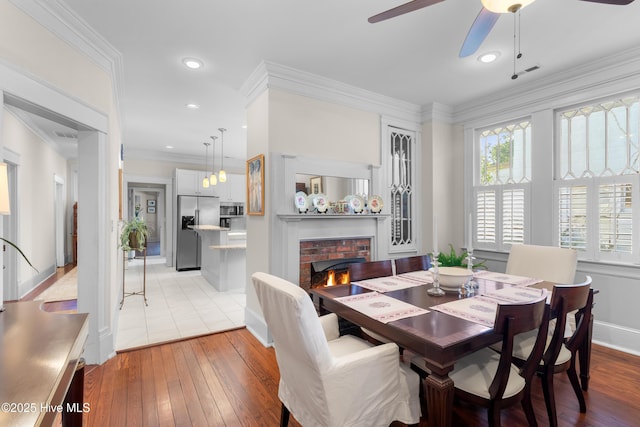 dining space with visible vents, light wood-type flooring, ceiling fan, and ornamental molding