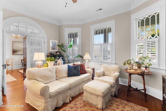 living area with visible vents, ceiling fan with notable chandelier, baseboards, and hardwood / wood-style floors