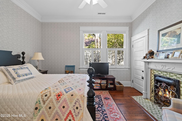 bedroom with dark wood-style floors, visible vents, wallpapered walls, a high end fireplace, and crown molding