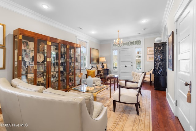 living area with an inviting chandelier, wood finished floors, visible vents, and ornamental molding