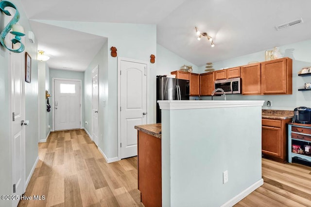 kitchen with stainless steel microwave, lofted ceiling, light wood-style floors, and visible vents