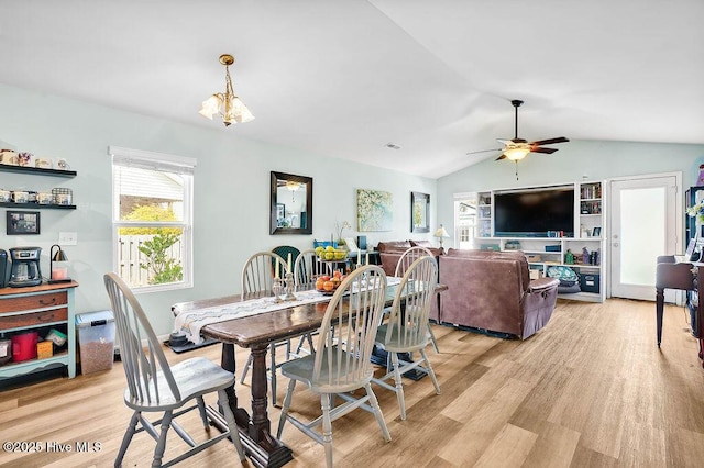 dining area featuring ceiling fan with notable chandelier, vaulted ceiling, and light wood-style floors