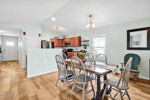 dining space with vaulted ceiling, light wood-style floors, and baseboards