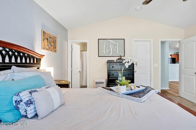 bedroom featuring vaulted ceiling, baseboards, and black refrigerator