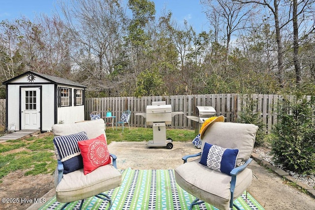 view of patio / terrace with an outbuilding, a storage unit, a fenced backyard, and grilling area