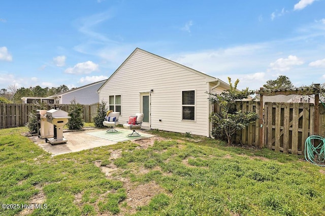 rear view of house with a patio, a lawn, and a fenced backyard