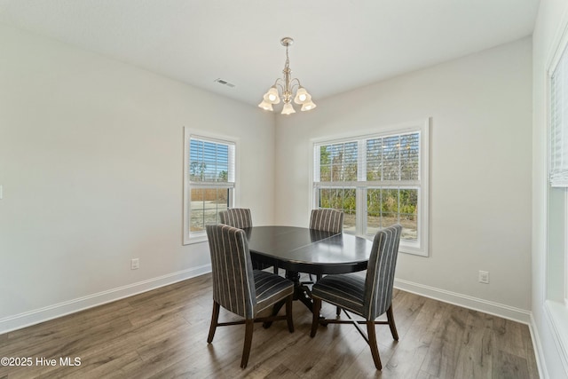 dining area featuring a chandelier, visible vents, baseboards, and wood finished floors